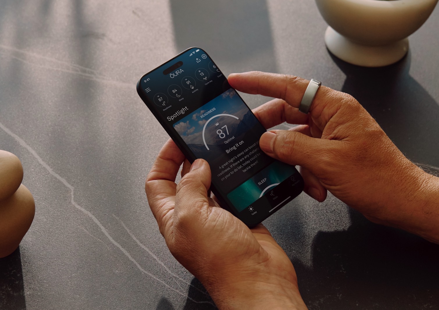 A person checking the Oura App on a smartphone.