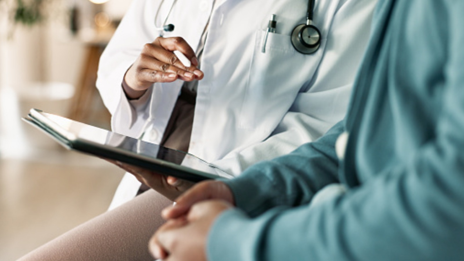 doctor talking to patient while holding a tablet